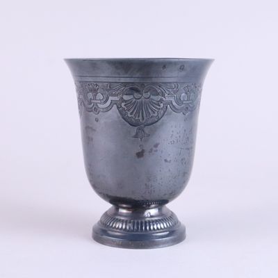 a silver vase sitting on a pedestal on a white surface