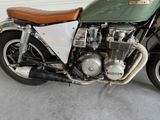 a green motorcycle parked in a garage with a brown seat