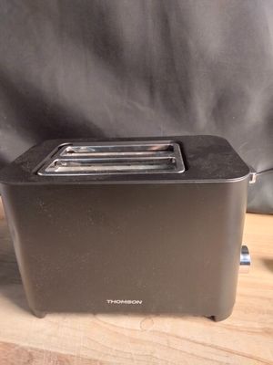 une photo d'un grille-pain posé sur une table, à côté d'une tasse de café