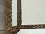 a gold framed mirror hanging on a wooden wall