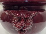 a red bowl with a face on it on a table