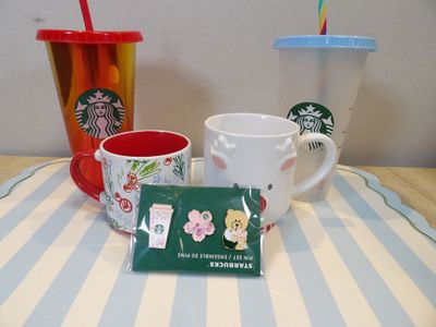 three starbucks mugs and a starbucks cup on a table