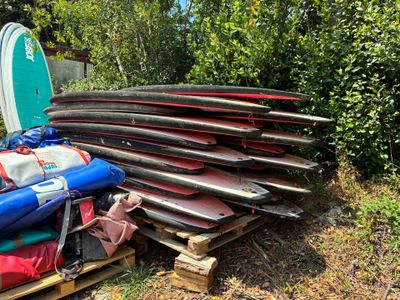 many surfboards stacked on a pallet in the grass