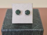 une paire de boucles d'oreilles en pierre verte posée sur un bloc de marbre