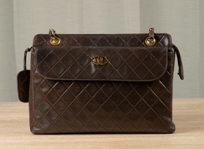brown chanel bag sitting on a table with a curtain in the background