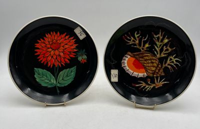 deux assiettes noires ornées de fleurs rouges et jaunes