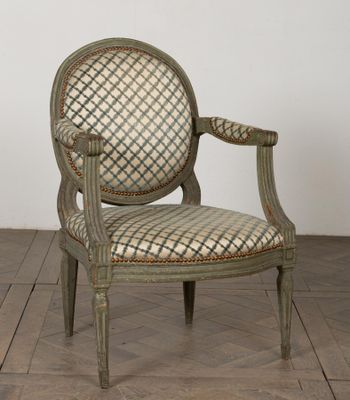 une vieille chaise dont le dossier et les accoudoirs sont recouverts d'un tissu à carreaux