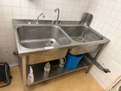 a stainless steel sink in a bathroom with two blue buckets on the floor