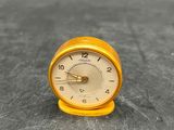 une petite horloge posée sur une table, sur fond noir