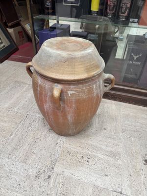 a large brown pot sitting on a table in front of a glass case