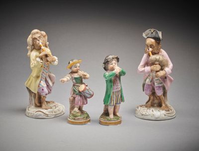 three porcelain figurines of people with hats and dresses on them