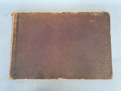 un vieux livre marron posé sur une table blanche
