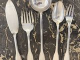 quatre fourchettes, une cuillère et un repose-cuillère posés sur une table
