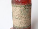 someone is holding a bottle of wine in their hand on a white surface