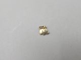 a close up of a small gold elephant charm on a white surface