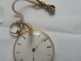 une montre de poche en or à laquelle est accrochée une chaîne sur le côté