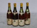 four bottles of wine are lined up on a marble surface