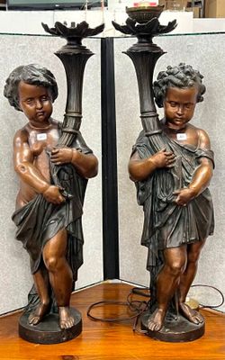 deux statues en bronze représentant un garçon et une fille, posées sur une table