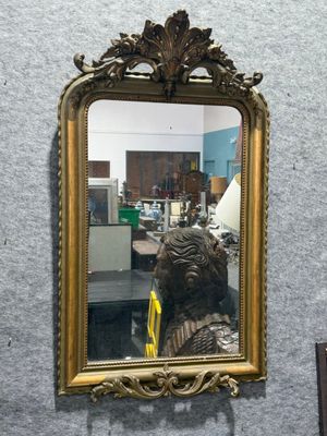 a mirror hanging on the wall with a statue in front of it