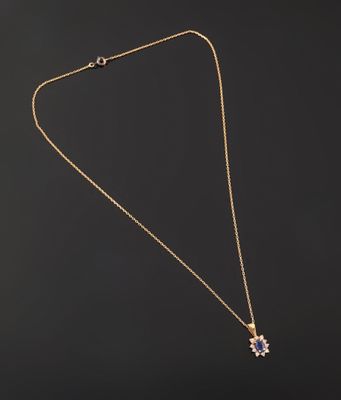 a gold necklace with a flower pendant on a black background