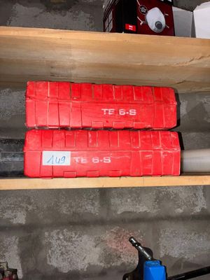 deux boîtes rouges posées sur une étagère à côté d'une machine bleue
