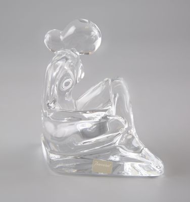 figurine en verre transparent représentant une femme assise sur un rocher, avec une fleur dans les cheveux