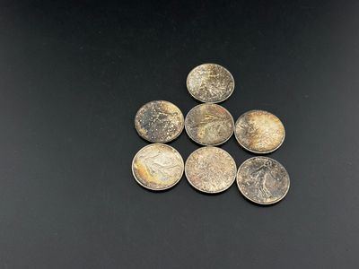 six silver coins sitting on top of each other on a black surface