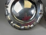 two silver plates sitting next to each other on a table