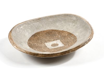 un bol marron et blanc posé sur une surface blanche