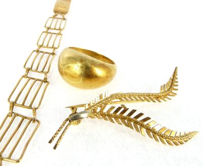 a gold bracelet and a gold ring on a white surface