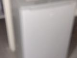 a small refrigerator with a coffee mug on top of it