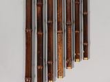 six bamboo flutes are lined up against a white wall