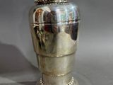 a silver vase sitting on a table with a silver lid