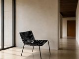une chaise noire placée dans une pièce dotée d'une grande fenêtre