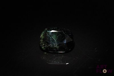 a black and green stone sitting on top of a black surface