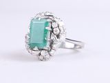 a close up of a ring with a green stone surrounded by diamonds