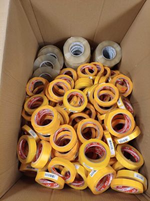 de nombreux rouleaux de ruban adhésif dans une boîte posée par terre