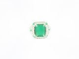 a close up of a ring with a green stone surrounded by diamonds
