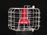 un objet rouge dans une cage blanche sur fond noir