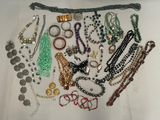 many different necklaces and bracelets laid out on a table