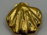 an image of a gold shell shaped object on a white surface