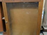 a wooden cabinet with a glass door on top of it