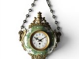 a clock hanging from a chain on a wall