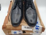 pair of black leather shoes sitting on top of a cardboard box