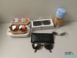 une boîte de lunettes de soleil, une tasse de café et une paire de lunettes de soleil posées sur une table