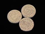 three silver coins sitting on top of each other on a black surface