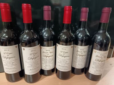 six bouteilles de vin rouge sont alignées sur une table