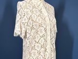 a white lace top on a mannequin stand against a blue wall
