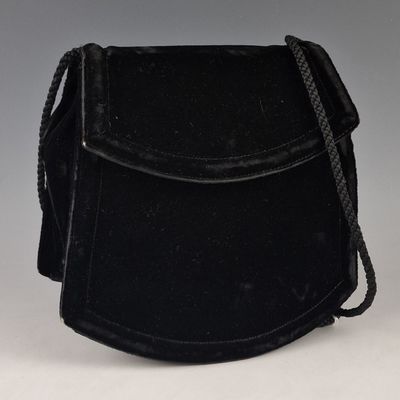 un vieux sac à main noir auquel est accrochée une chaîne sur le côté
