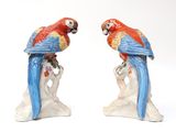 two figurines of parrots sitting on top of a tree stump